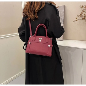 Deep red lychee grain leather handbag with silver lock shown on a model's shoulder
