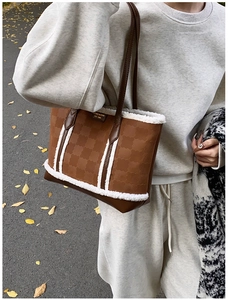 Detail of brown embossed tote bag with white faux shearling trim and long leather handles