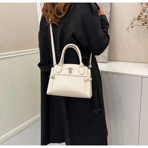 Detail of cream lychee texture leather handbag with metal lock on black coat