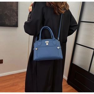 Detailed view of deep blue leather bag with pebble texture and metallic lock accessory