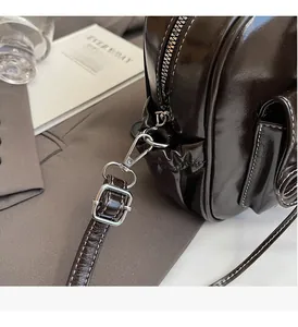 Detail of glossy coffee leather handbag with silver hardware and white contrast stitching