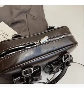 Detail of silver smooth metal zipper and side buckle on dark brown glossy tote bag