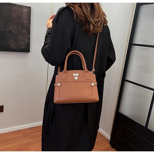 Brown litchi grain handbag with metal lock shown in a stylish over-the-shoulder pose