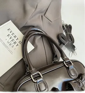 Detail of dark brown patent leather handbag with contrast stitching and silver hardware