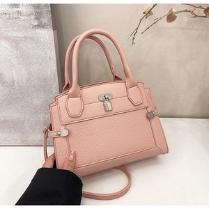 Detail of pink lychee grain leather handbag featuring silver lock and metal rivets