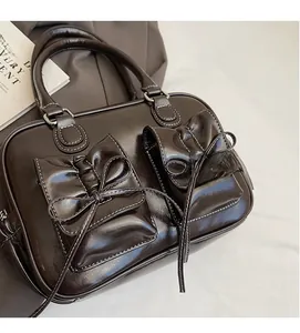 Detail of dark brown oil wax leather handbag featuring elegant bow-knot pockets