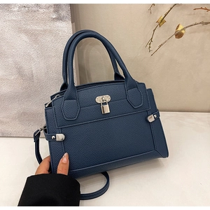 Detail view of navy blue pebbled leather handbag with silver lock and double handles