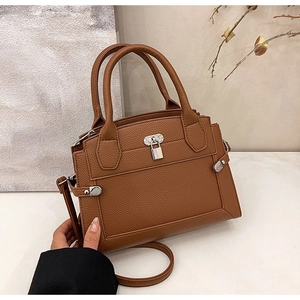 Detail view of caramel brown lychee leather texture and silver lock on handbag