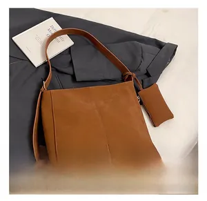 Close-up of brown suede tote bag with dual vertical stitching and matching mini pouch accessory