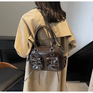 Detail of dark brown bow handbag with dual pockets and polished PU leather finish