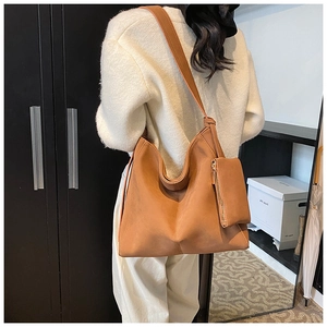 Brown vintage leather tote bag with vertical V-stitch and matching pouch shown on shoulder