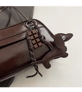 Detail of dark brown oil wax leather bag with chocolate and dachshund charm accents