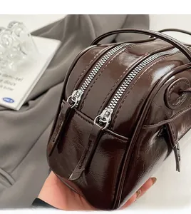 Detailed close-up of smooth silver double zippers on dark brown PU leather shoulder bag