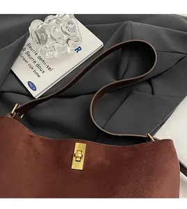 Détail du sac hobo en daim marron avec fermoir rotatif doré et bandoulière en cuir