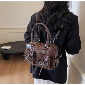 Detail view of glossy dark brown leather backpack with bow-knot pockets and metal hardware