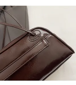 Detail of hand-stitched seams and smooth edge finish on dark brown PU leather bag