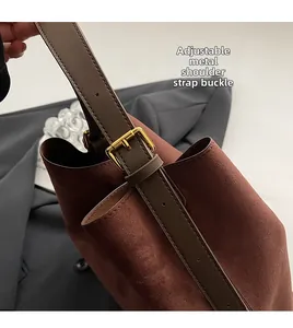 Gros plan de la boucle métallique réglable sur la bandoulière du sac en daim marron