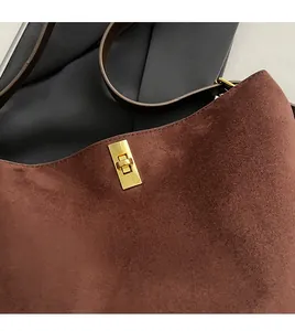 Gros plan sur la boucle en métal doré et le daim marron de ce grand sac fourre-tout