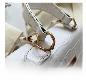 Detail of white crocodile texture leather with gold D-ring and lobster clasp hardware