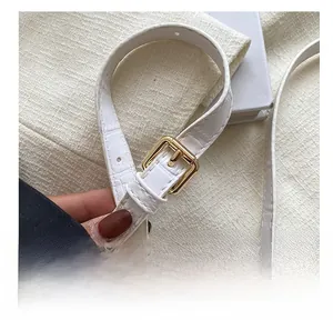 Detail of white crocodile embossed leather strap with adjustable gold buckle