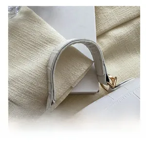 Detail of white crocodile texture leather handbag featuring a gold metal twist lock buckle