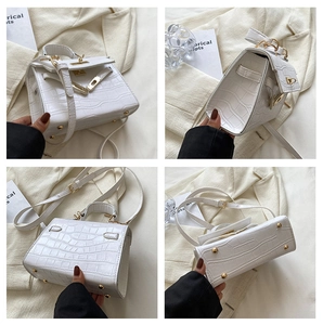 Detailed views of white crocodile pattern handbag with gold hardware and trapezoid shape