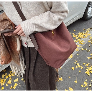 Détail du sac cabas en daim bordeaux avec boucle en métal doré et bandoulière en cuir