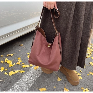 Détail du sac cabas en daim bordeaux avec bandoulière en cuir brun sur feuilles de ginkgo