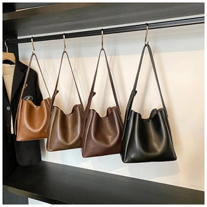Minimalist leather bucket bags in four colors hanging on a modern metal display rack