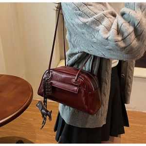Detail of burgundy PU leather Boston bag featuring chocolate and dachshund charms