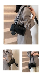 Detail view of a black glossy rectangular tote bag with matching mini pouch charm