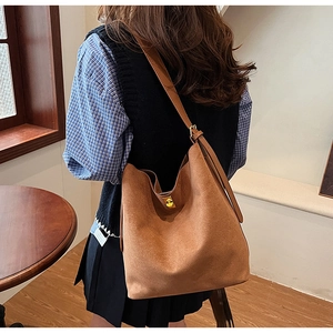 Détail d'un sac cabas en daim marron avec bandoulière réglable et boucle carrée dorée