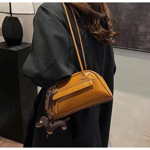 Close-up of ginger yellow PU leather shoulder bag with dark brown dachshund dog charm
