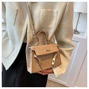 Detail of crocodile embossed leather texture with golden hardware on a Kelly handbag