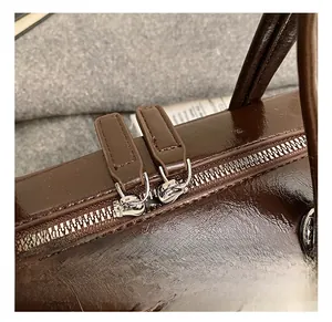Macro shot of dark brown polished leather texture and silver dual zippers on the pillow bag