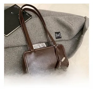 Detail of dark brown glossy leather tote bag with matching small hanging charm