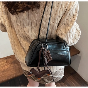 Detail of glossy black PU shoulder bag featuring cute chocolate and dachshund charms