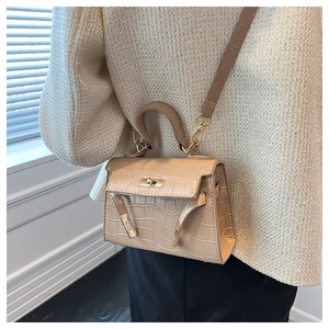 Detailed view of crocodile pattern Kelly bag with gold metal hardware and crossbody strap