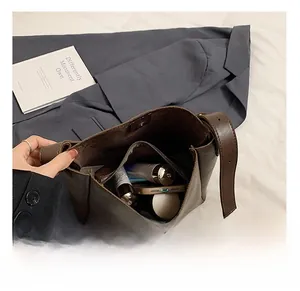 Detail of spacious dark brown PU leather bag interior with zipper divider and daily items