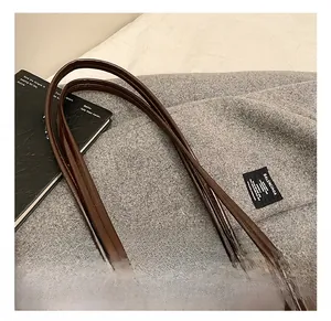 Detail of dark brown leather handle with neat stitching and silver metal ring hardware
