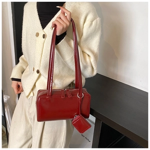 Detail of red glossy leather pillow bag featuring a mini coin pouch and dual zippers
