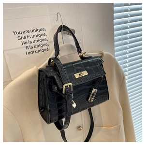 Detail of black crocodile-embossed bag featuring gold-tone lock on white coat