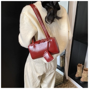 Detail of burgundy patent leather tote with matching mini pouch on a white sweater