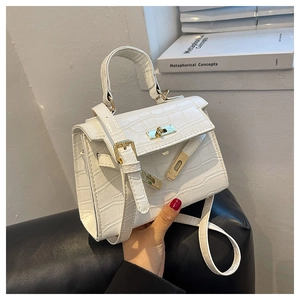 Detail of white crocodile embossed texture on a mini trapezoid handbag with gold hardware