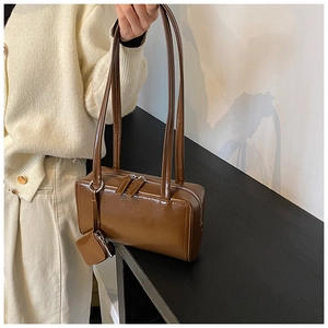Detailed shot of brown faux leather shoulder bag with sleek finish and mini pouch