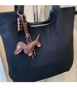 Gros plan détaillé d'un cabas en daim noir avec des breloques en cuir décoratives