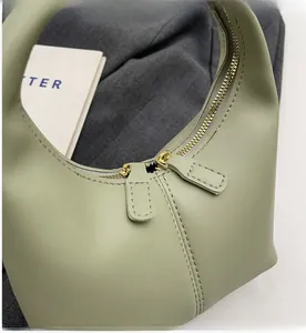 Close-up of smooth metal dual zippers on a matte sage green leather handbag detail