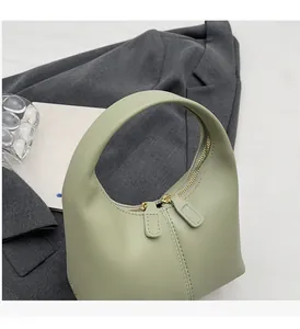 Detailed view of light green leather handbag featuring double gold zipper closure