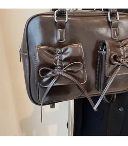 Detail of dark brown glossy PU tote bag featuring bow pockets and contrast white stitching