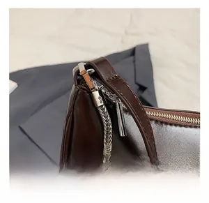 Detail of glossy dark brown leather bag showing silver hardware hooks and chain strap